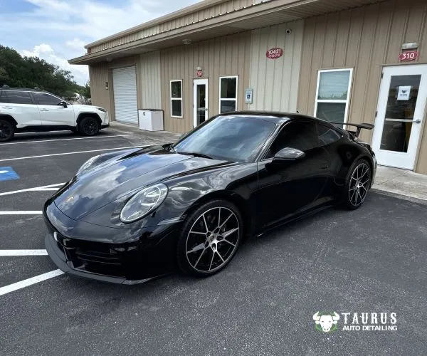 view of a glossy black Porsche coupe with dark tinted windows parked outside